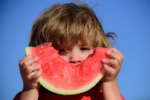 Primer plano de un niño gracioso comiendo sandía dulce