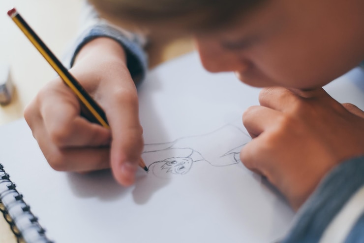 Foto primer plano de un niño haciendo un boceto en un bloc de notas
