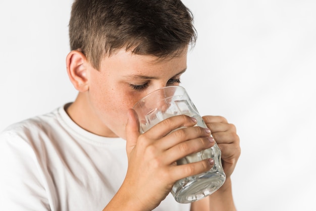 Primer plano de un niño con leche en vaso sobre fondo blanco