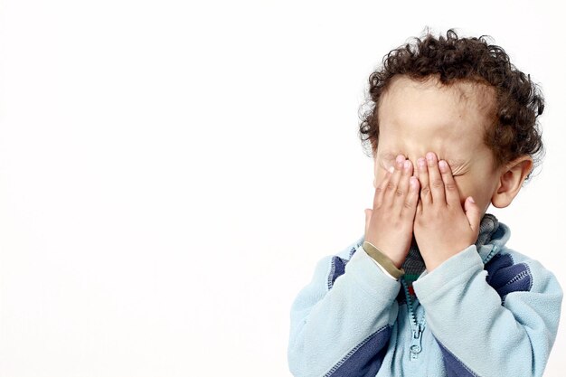 Foto primer plano de un niño llorando contra un fondo blanco