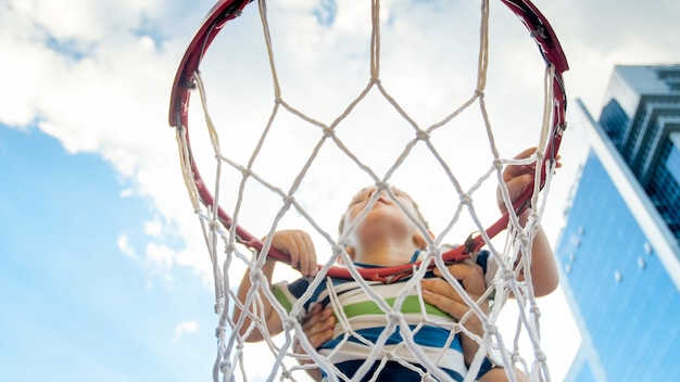 Primer plano de un niño pequeño de 3 años activo sosteniendo el anillo de la red de baloncesto