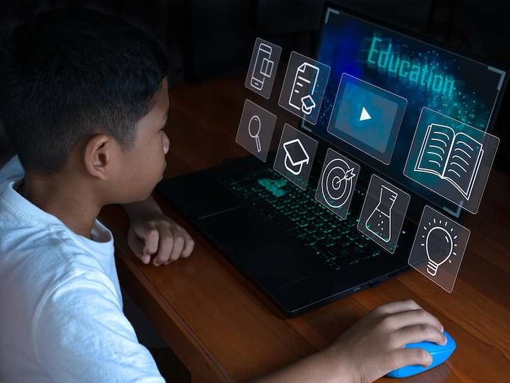Foto primer plano el niño se sienta mirando la computadora portátil y su mano sostiene el mouse educativo.
