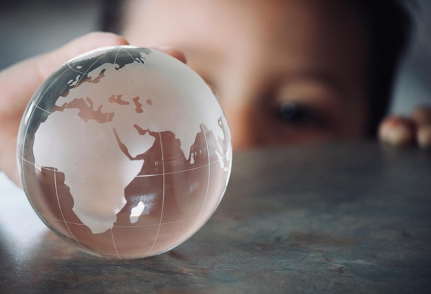 Primer plano de un niño sosteniendo un globo de vidrio en la mesa