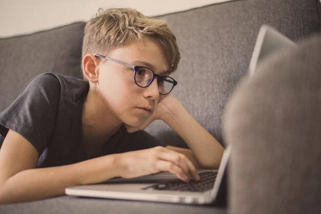 Primer plano de un niño usando una computadora portátil en el sofá