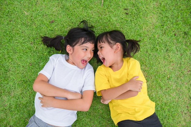 Primer plano de niños asiáticos felices tumbado sobre la hierba verde