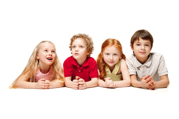 Primer plano de niños felices acostado en el piso en estudio y mirando hacia arriba, aislado sobre fondo blanco. Emociones de los niños, día del libro, educación, escuela, niño, conocimiento, infancia, amistad, concepto de estudio