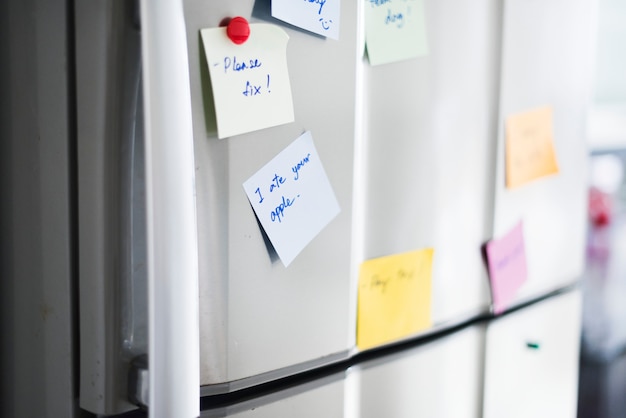 Primer plano de la nota de papel recordatorio en la puerta del refrigerador