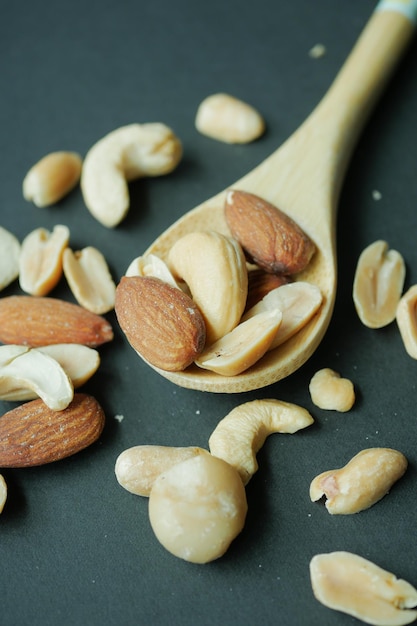 Primer plano de nueces de almendras en una cuchara de madera sobre fondo negro