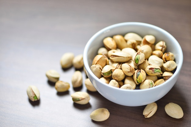 Primer plano de las nueces de pistacho en un tazón blanco sobre fondo de madera