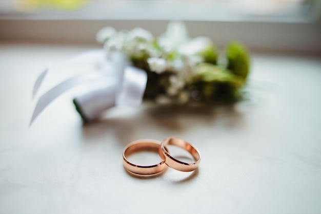 Primer plano de ojal y anillos de boda de oro
