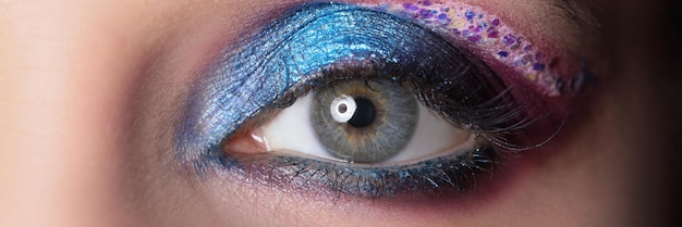 Primer plano del ojo femenino con brillantes sombras púrpuras concepto de maquillaje profesional