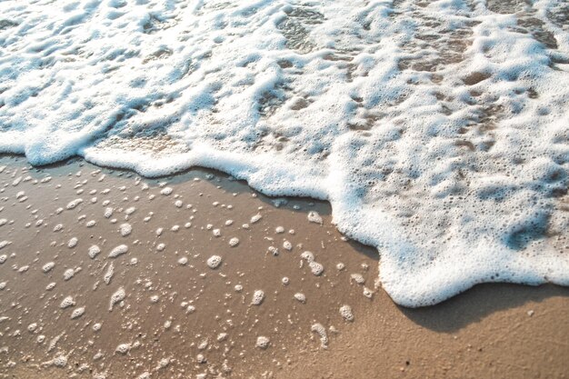 Primer plano de la ola de mar con espuma en la arena de la playa Fondo de vacaciones de verano