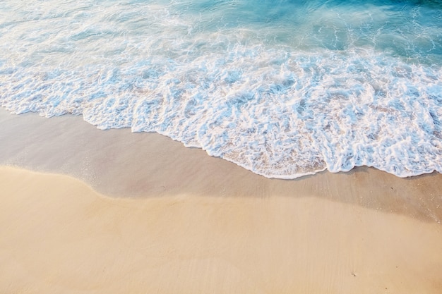 Primer plano de la orilla del mar. Hermosa agua azul con espuma cerca de la orilla arenosa. Lugar para el texto. El concepto de recreación marina, vacaciones o turismo. Vista superior.