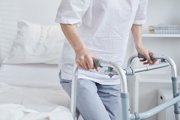 Foto primer plano del paciente de pie con el andador desde la cama del hospital