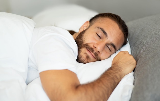 Foto primer plano de un pacífico hombre milenario durmiendo en la cama en casa