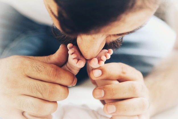 Foto primer plano del padre besando las piernas del bebé