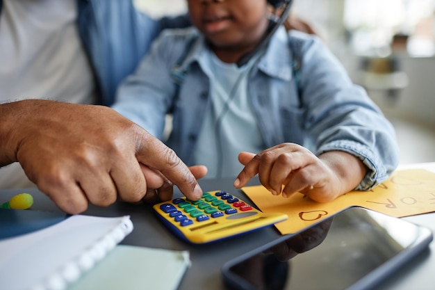 Primer plano de padre e hijo jugando con calculadora de juguete aprendiendo a contar y trabajar