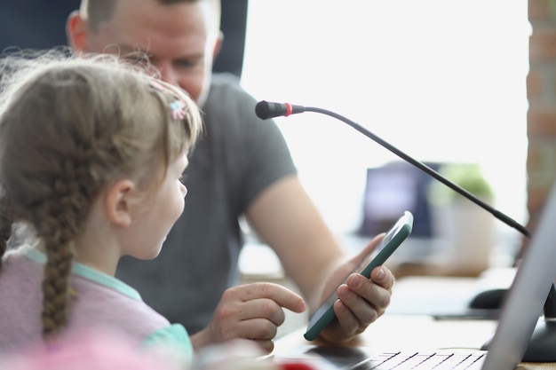 Primer plano de padre mostrando video divertido a hija en smartphone. Enseñar a los niños a usar el teléfono móvil. Tiempo entre padres e hijos, tiempo de calidad, tecnología, pasatiempo, concepto de infancia