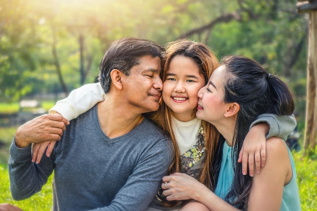 Foto primer plano de padres besando a su hija en el parque