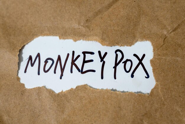 Foto primer plano de la palabra viruela del mono expuesta desde un agujero de papel que representa el brote de la enfermedad