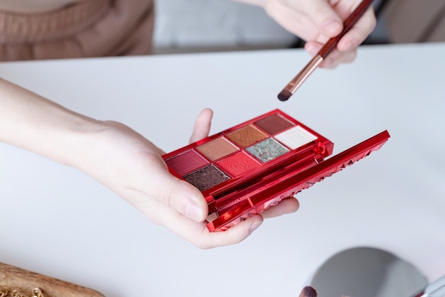 Primer plano de la paleta de sombras de ojos con colores vivos en la mano de la mujer