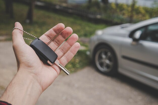 Primer plano de la palma de la mano sosteniendo la llave del auto en un auto estacionado El conductor de fondo sostiene la llave del vehículo en t