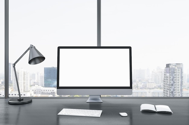 Primer plano de la pantalla de la computadora blanca en blanco en el escritorio de la oficina gris con lámpara de objetos y suministros en la ventana panorámica y el fondo de la vista de la ciudad Mock up 3D Rendering