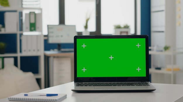 Primer plano de la pantalla verde en la computadora portátil en el escritorio vacío. Nadie en el escritorio con clave de croma y plantilla de maqueta aislada, fondo en blanco en la computadora portátil. Espacio comercial con pantalla chromakey.