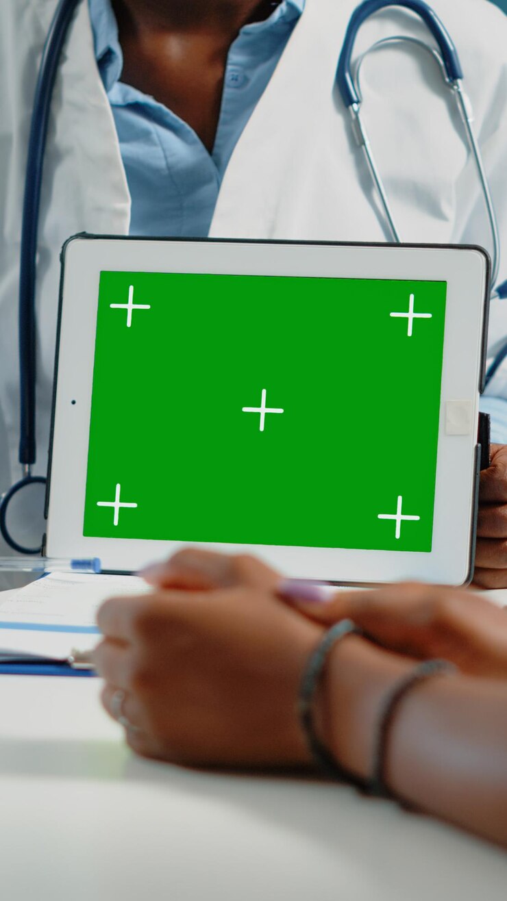 Foto primer plano de la pantalla verde horizontal en la tableta digital en la visita de control. doctor apuntando a la plantilla de maqueta con clave de croma y fondo aislado para mostrar la tecnología al paciente.