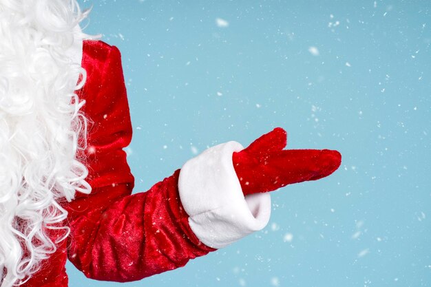 Un primer plano de Papá Noel mostrando la nieve aislada sobre la nieve de fondo azul