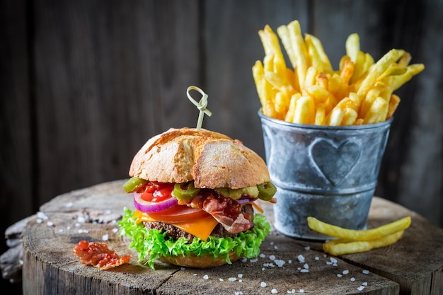 Primer plano de papas fritas y hamburguesa con tocino, tomate y carne de res