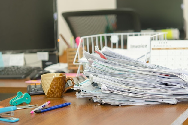 Primer plano de papeles apilados y suministros de oficina en el escritorio