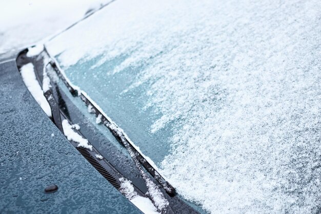 Foto un primer plano del parabrisas del coche y los limpiaparabrisas cubiertos de hielo y nieve en un día de invierno