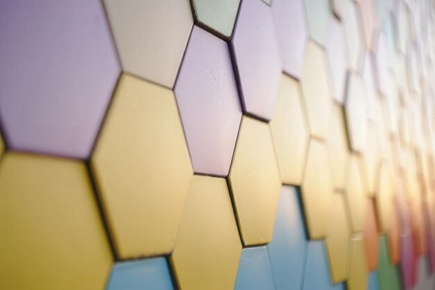 Un primer plano de una pared con azulejos hexagonales de color pastel dispuestos en un patrón repetitivo