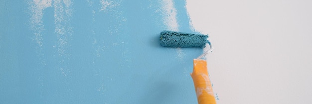 Primer plano de una pared de pintura de decorador profesional en paredes de pintura de color azul con reparación de rodillos