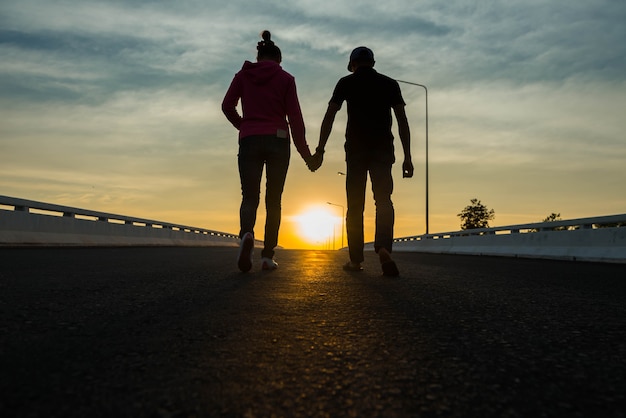 Primer plano de una pareja amorosa cogidos de la mano mientras camina al atardecer