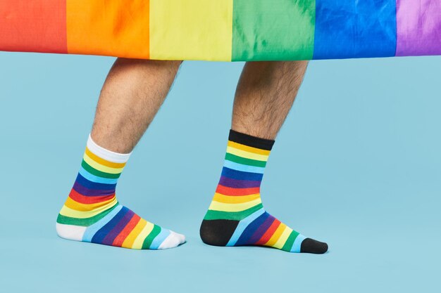 Primer plano de una pareja con calcetines de arco iris con bandera lgbtq sobre fondo azul pastel