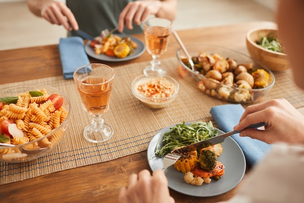 Primer plano de pareja comiendo una cena saludable y bebiendo vino en la mesa en casa