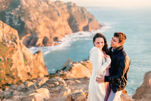 Primer plano pareja enamorada, linda sonrisa y abrazo en la orilla rocosa del océano