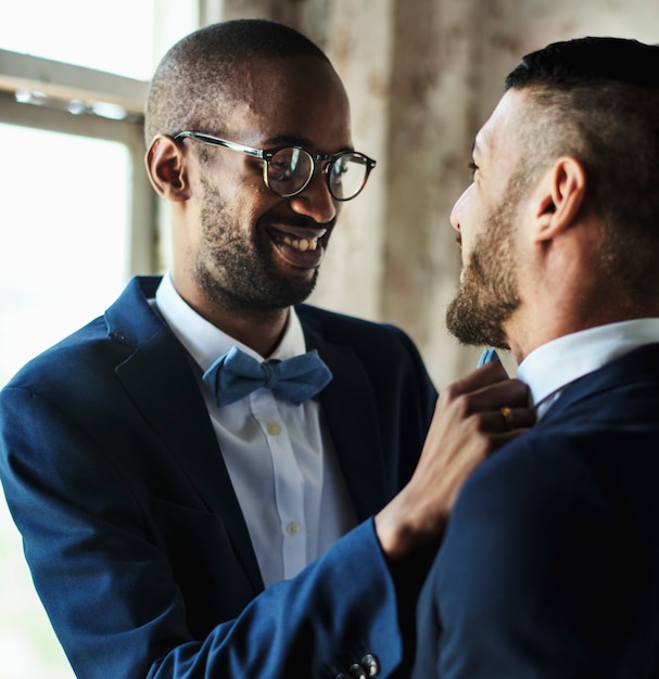 Primer plano de una pareja gay ayudándose mutuamente a vestirse