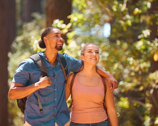 Un primer plano de una pareja joven y activa que lleva mochilas caminando por un sendero a través del campo.