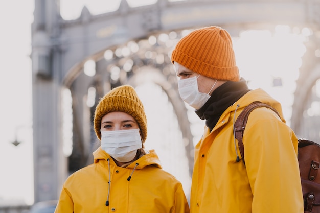 Primer plano de una pareja joven con máscaras quirúrgicas protectoras y chaquetas amarillas que están molestos y han perdido su trabajo debido a la pandemia del virus. Concepto de virus Covid-19.