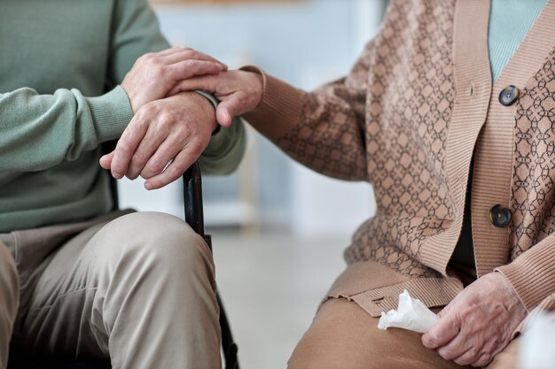 Primer plano de una pareja mayor tomándose de la mano durante la sesión de terapia