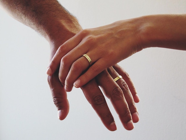 Primer plano de una pareja que se toman de la mano contra un fondo blanco
