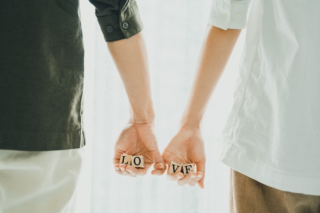 Foto primer plano de la pareja tomados de la mano las letras de amor