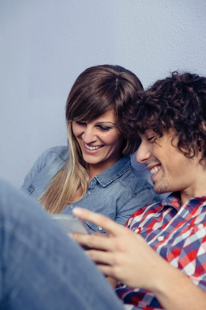 Foto primer plano de una pareja usando una tableta digital mientras se apoya en la cama en casa