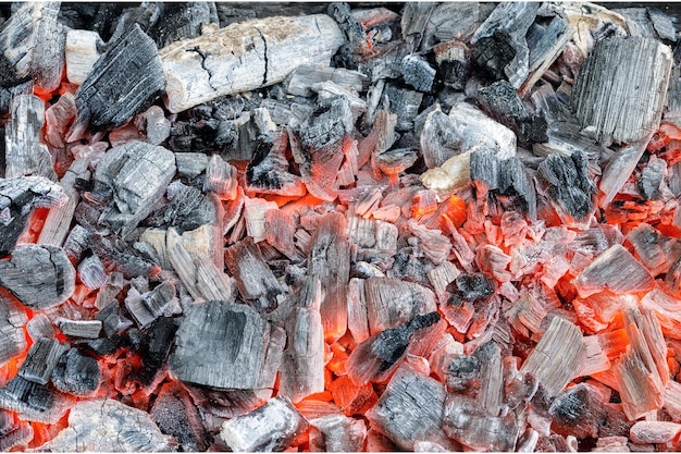 Un primer plano de una parrilla de carbón con brasas rojas.