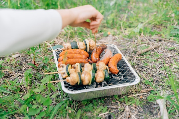 Primer plano de parrilla de un solo uso para picnic al aire libre con verduras en palo de madera