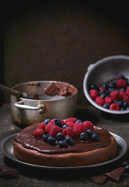 Primer plano de un pastel de chocolate con bayas frescas y crema de chocolate servido en la mesa