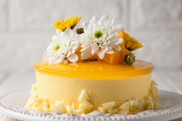 Primer plano de un pastel de mousse de mango amarillo con decoración floral